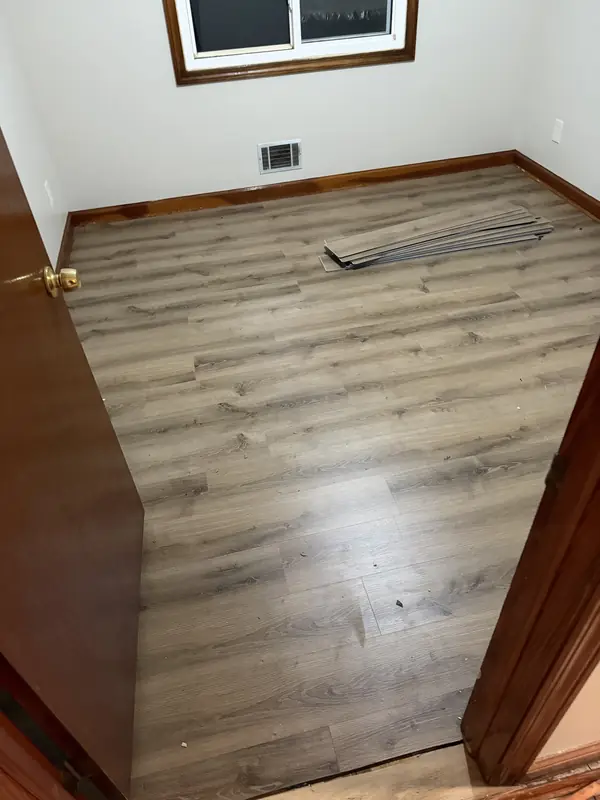 Gray luxury vinyl plank flooring being installed in a bedroom